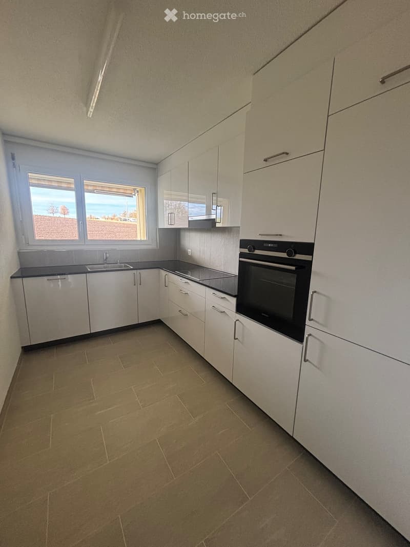 Modern kitchen with light-colored cabinets, a microwave, and a window offering a scenic view.