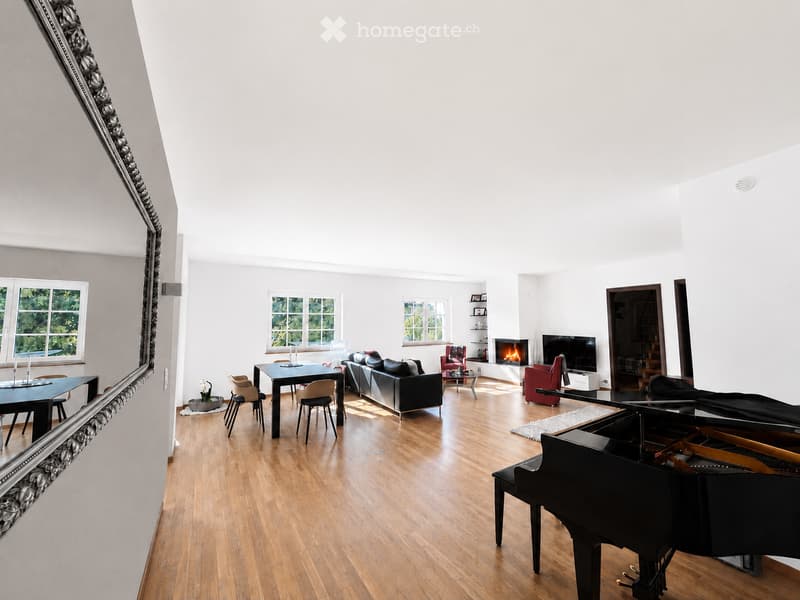 Bright, open living space with wooden flooring, large windows, a black grand piano, a fireplace, a sofa, a dining table, and chairs.