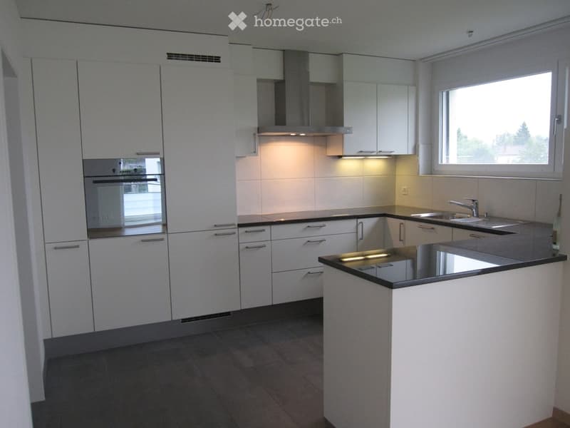 modern kitchen with white cabinets, black countertops, stainless steel appliances, large window