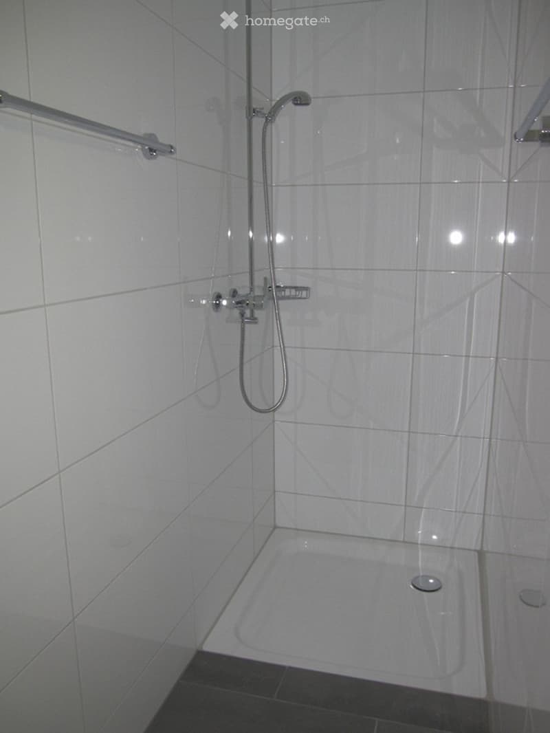 white tiled walls, white shower tray, silver shower head, silver shower rail