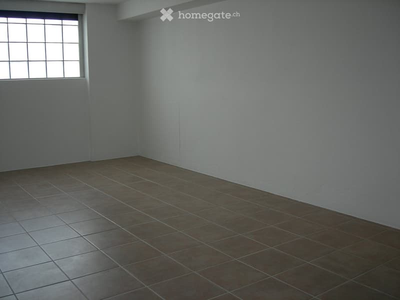 Empty room with tiled floor and single window, no furniture or equipment.