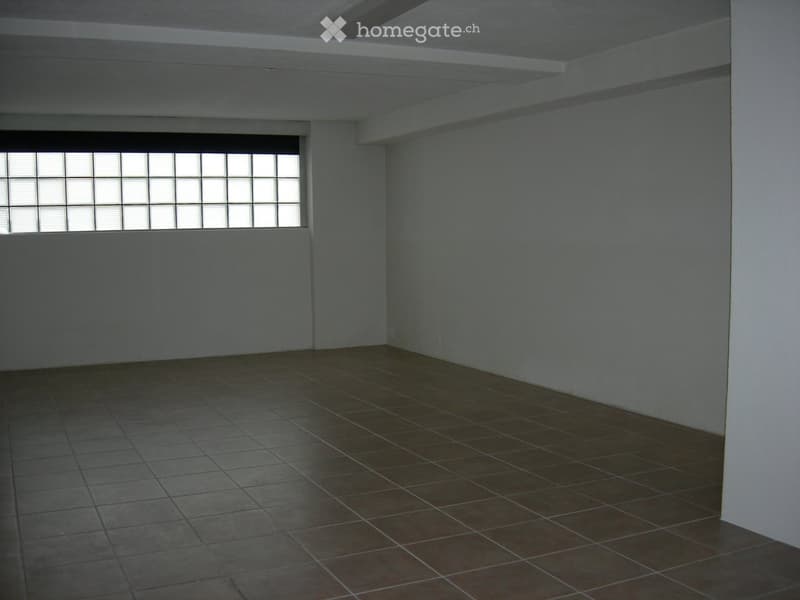 Empty room with tiled floor and large window with blinds. Bare walls and no furniture.