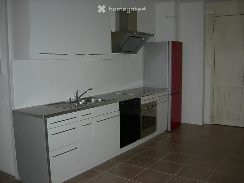 Modern kitchen with white cabinets, stainless steel appliances, and a dark countertop.