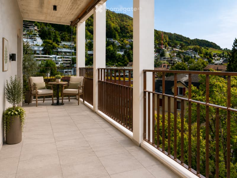 Balcony with tiled floor, wooden railing, two chairs, small table, and potted plants, overlooking a scenic town and green hills.