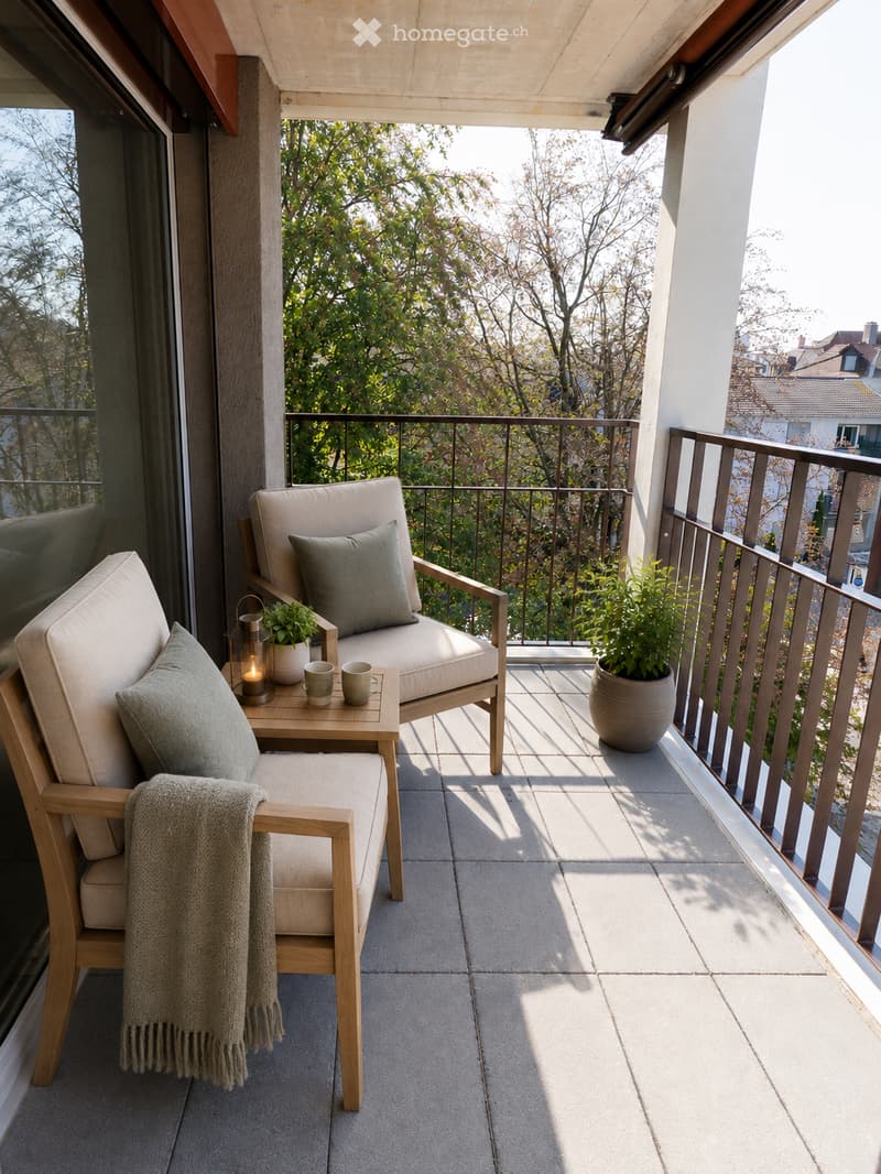 A modern balcony with two wooden chairs, a small table, two cups, a lantern, and potted plants. The balcony has a tiled floor and a metal railing, with a view of trees and buildings.