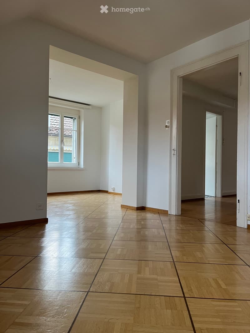 Empty room with wooden flooring, white walls, and large windows. No furniture or equipment present.