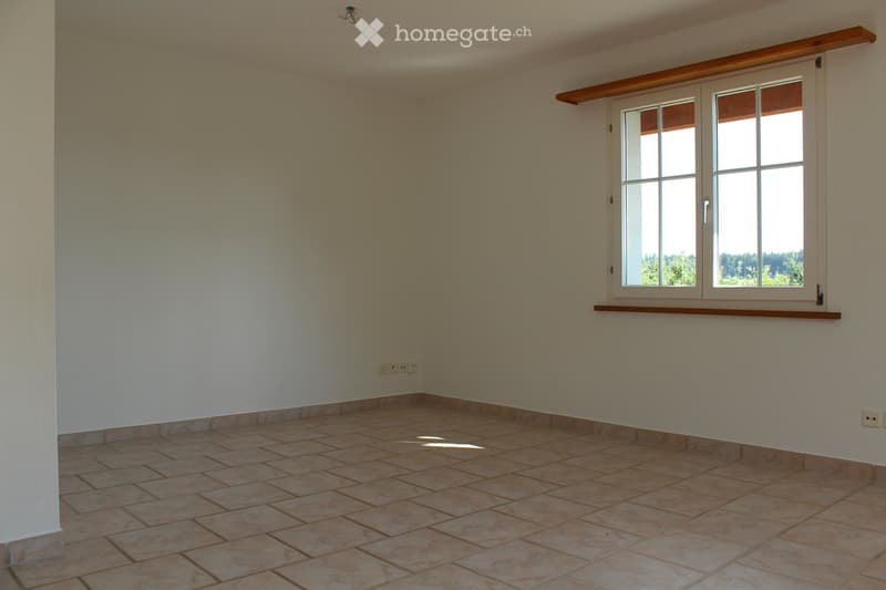 Empty room with tiled floor, white walls, and large window with wooden frame and sill.