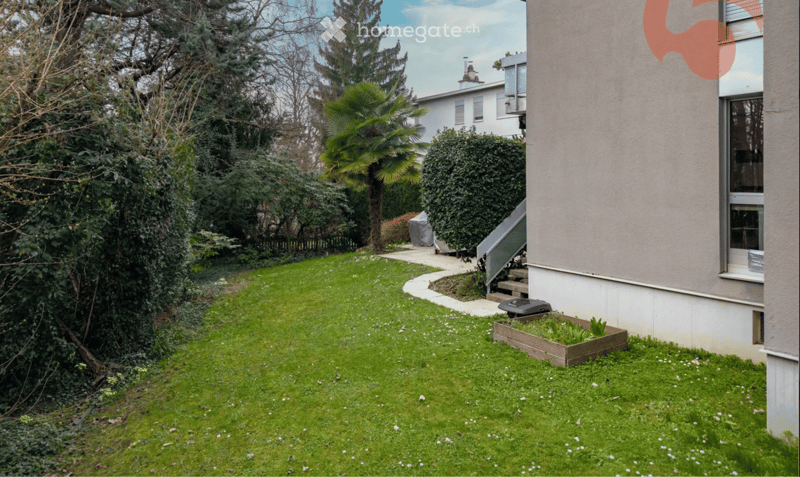 Well-maintained garden with a lawn, small raised planter, and a pathway leading to a house entrance.