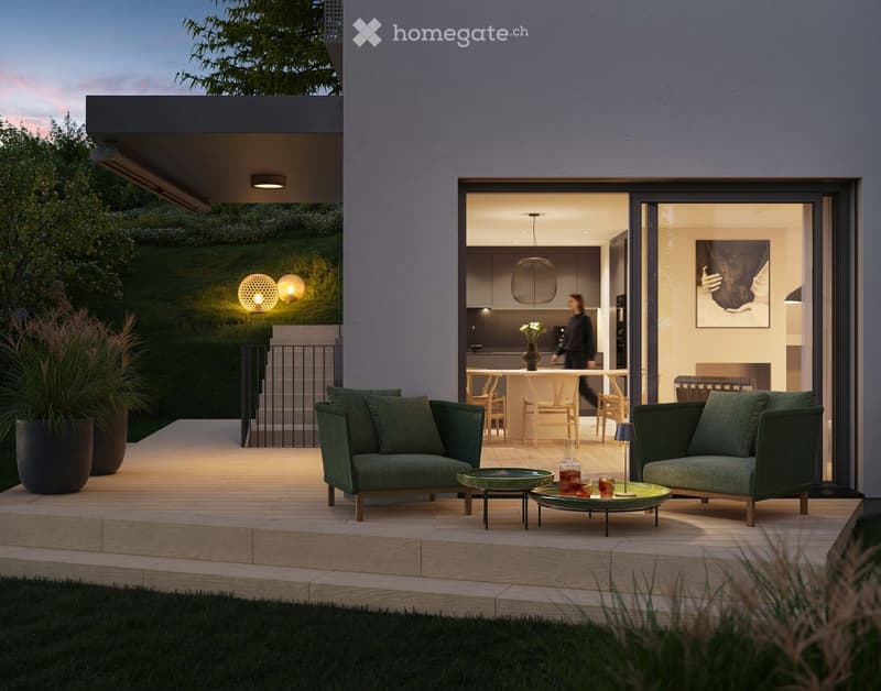 Modern living room with large windows, wooden floor, sofa, outdoor lounge chairs, coffee tables, decorative lights, kitchen area visible through the windows.