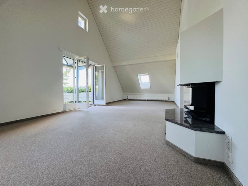 Empty room with carpeted floor, white walls, and large windows, including a fireplace with a black glass surround and a white cabinet base.