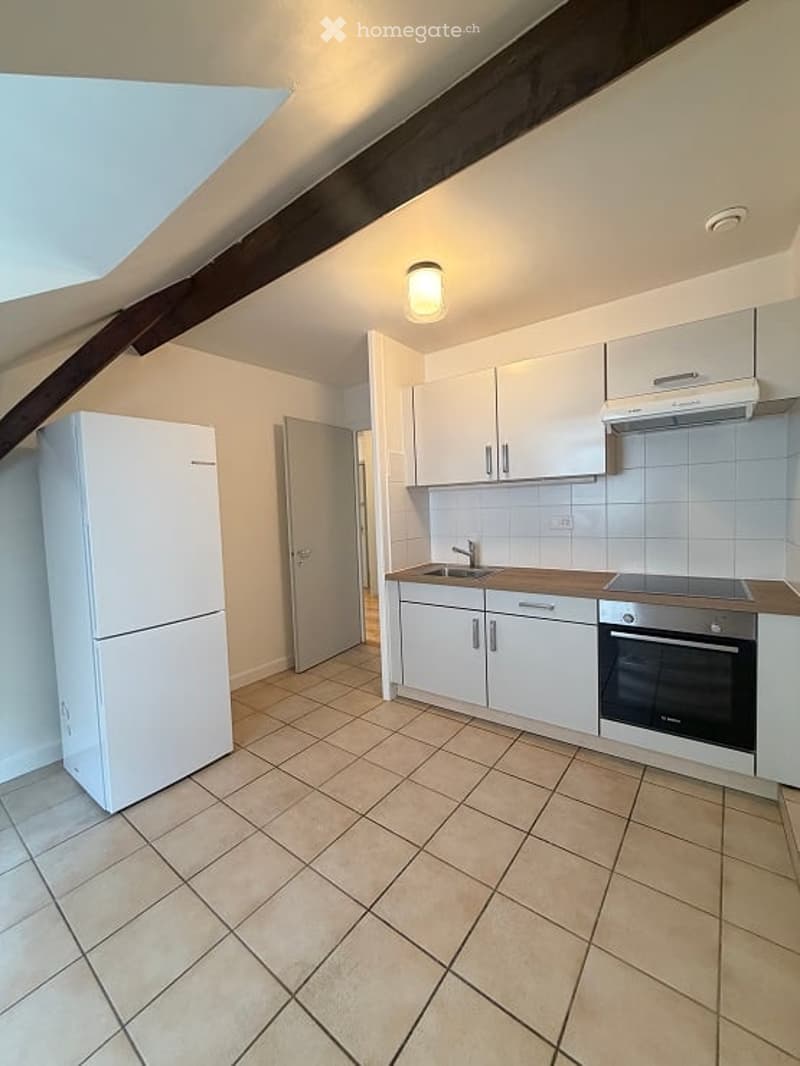 Modern kitchen with white cabinets, a stainless steel sink, a refrigerator, and an oven. The space features tiled flooring and exposed wooden beams on the ceiling.