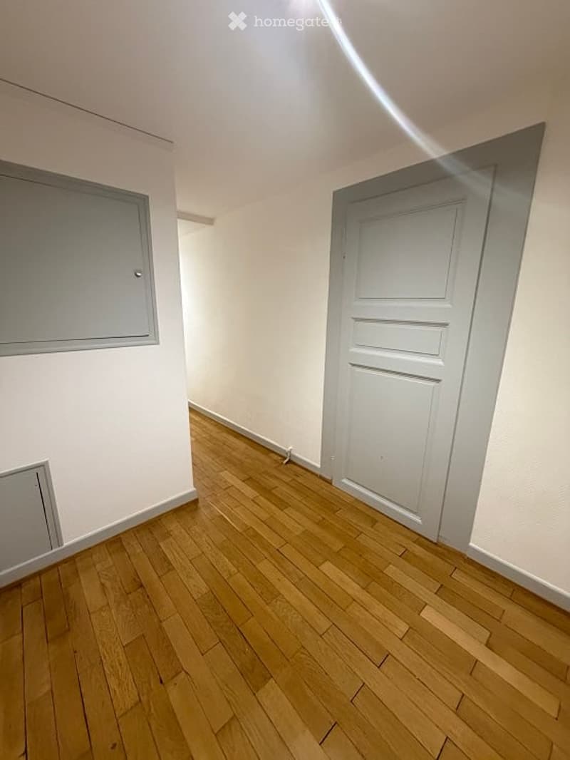 Empty room with wooden flooring, white walls, and a closed door. No furniture or equipment present.