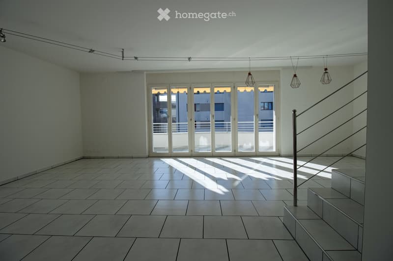 Empty room with tiled floor, white walls, large glass doors leading to a balcony, and modern pendant lights.