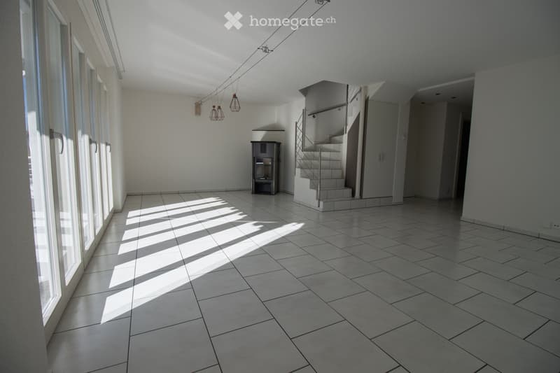 Empty room with tiled floor, large windows, staircase leading to another level, and a small cabinet.