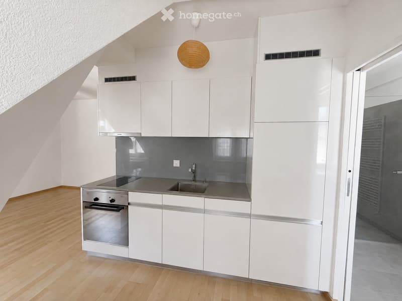 Modern kitchen with white cabinets, stainless steel appliances, and a wooden floor.