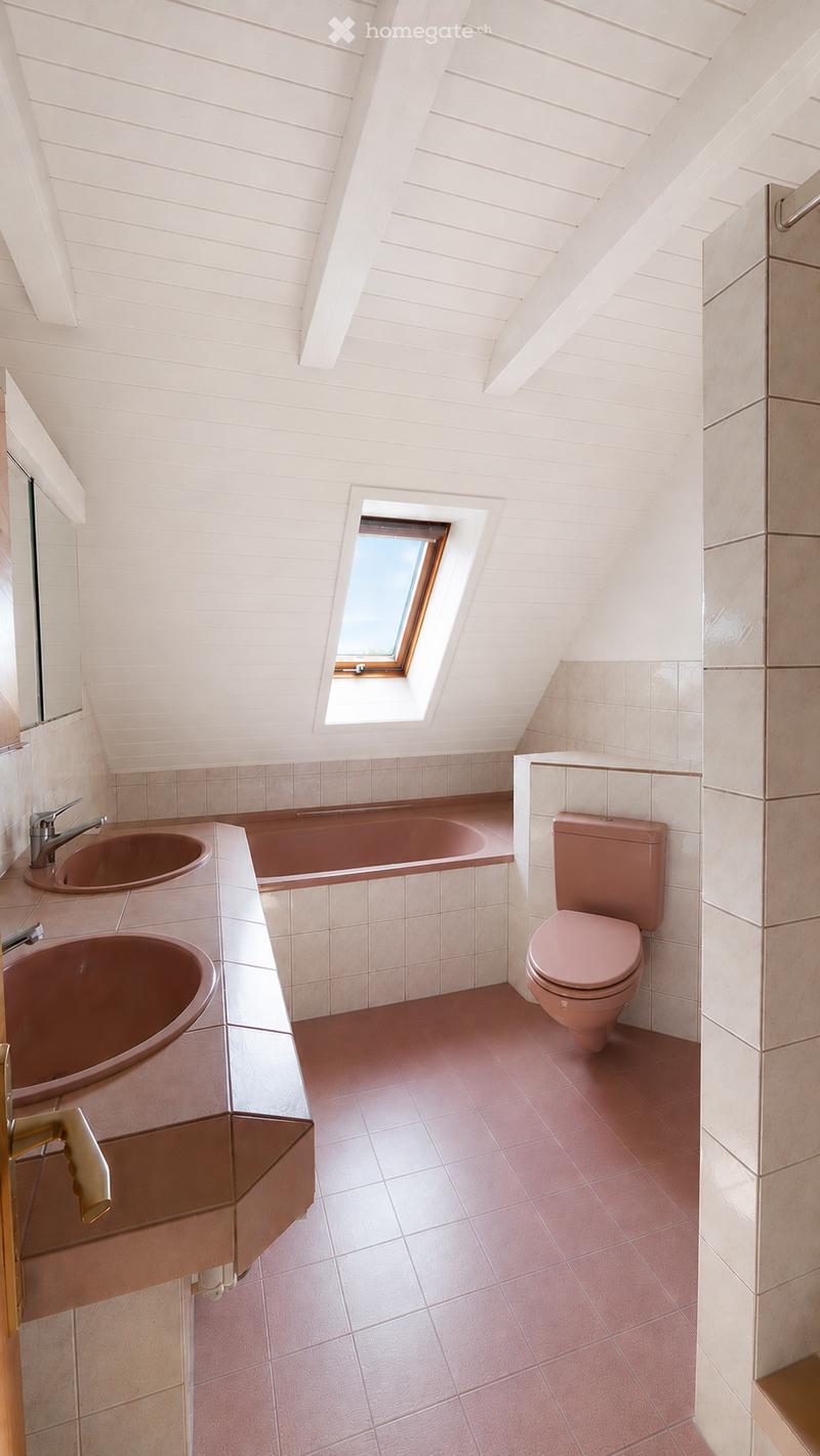 Modern bathroom with pink tiles, a bathtub, two sinks, a toilet, and a skylight window.