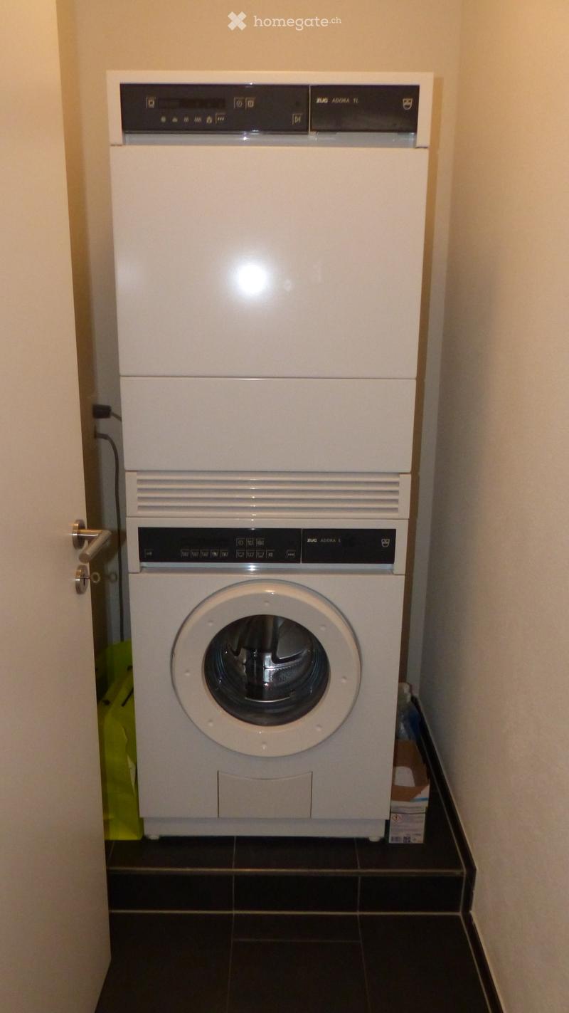 Stacked white washing machine and dishwasher against a wall in a corner