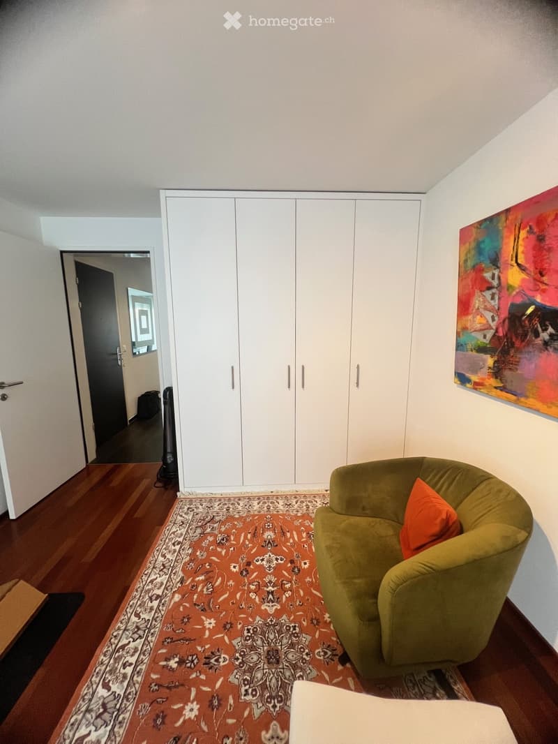 floor rug, large green chair, white built-in wardrobe, modern artwork, wooden flooring