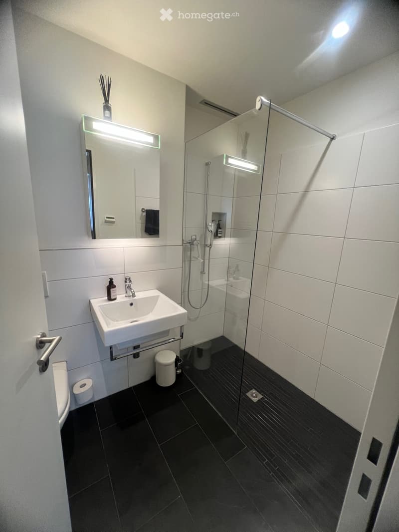 Modern bathroom with shower, sink, toilet, and white tiles
