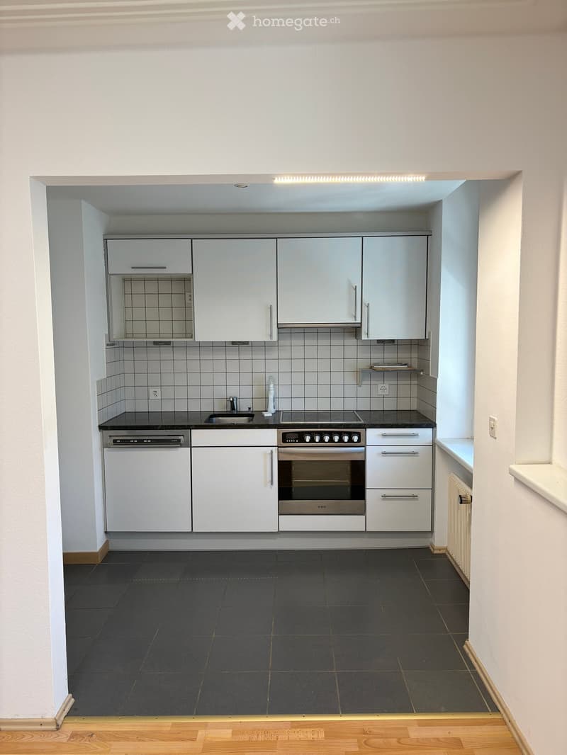 Modern kitchen with white cabinets, stainless steel appliances, dark countertops, and tiled backsplash.