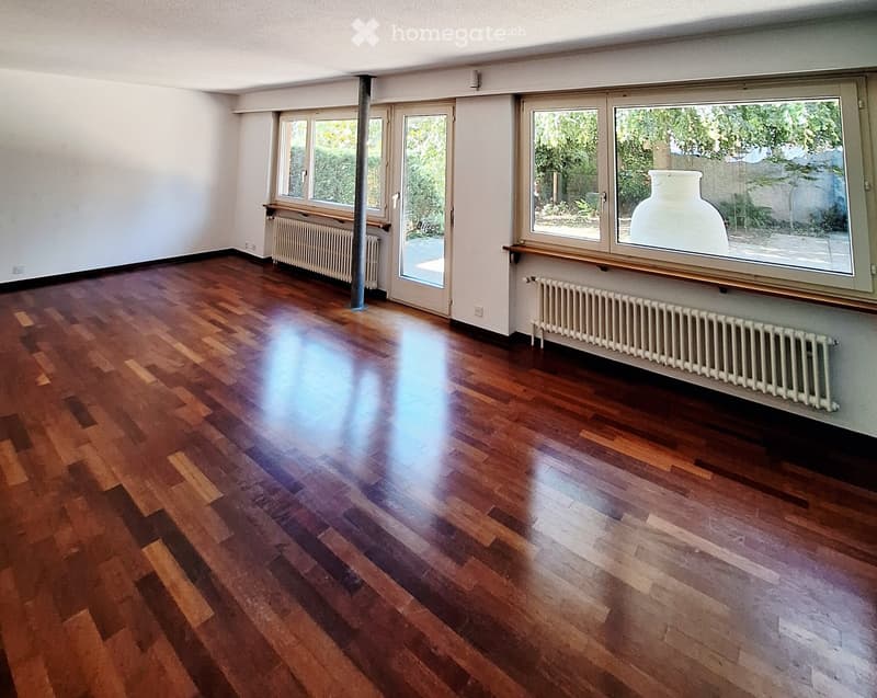 Empty room with wooden flooring, large windows, and radiators. No furniture or equipment present.