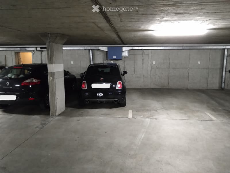 Underground parking area with two parked cars, concrete pillars, and numbered parking spots.