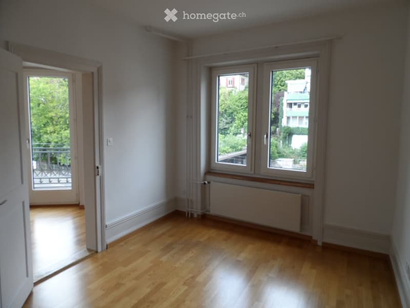 Empty room with wooden flooring, large windows, and a balcony access. No furniture or equipment present.