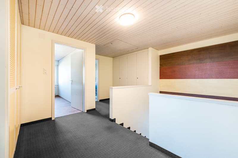 Empty room with light-colored walls, wooden ceiling, grey carpeted floor, and white cabinetry. No furniture or personal items present.