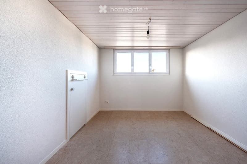 Empty room with white walls, a single window, a door, and a light fixture on the ceiling.