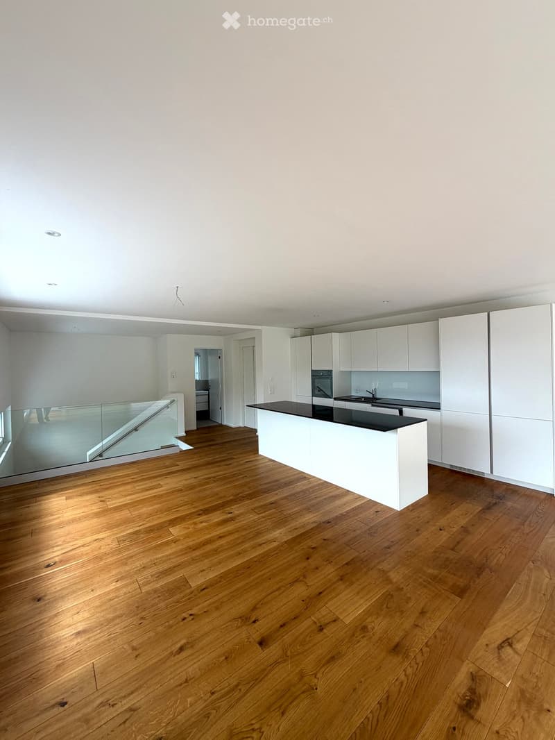 Modern kitchen with white cabinets, a black countertop island, and wooden flooring.