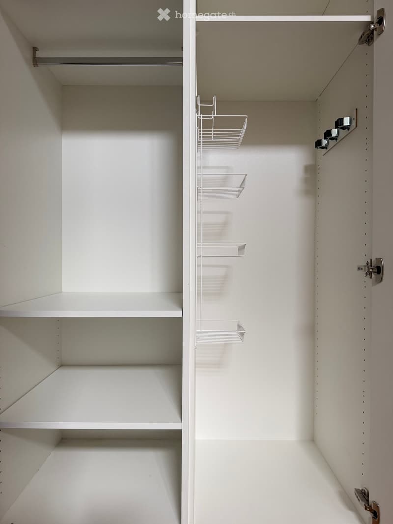 Empty white closet with multiple shelves and wire baskets on one side.
