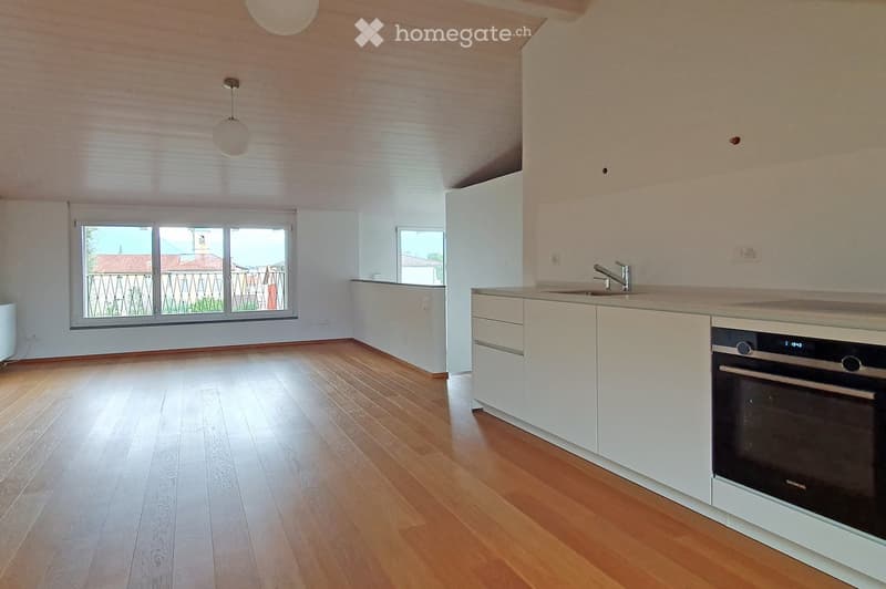 Modern kitchen with white cabinets, wooden flooring, and large windows offering a view of the outside. Features a sink, faucet, and an oven.