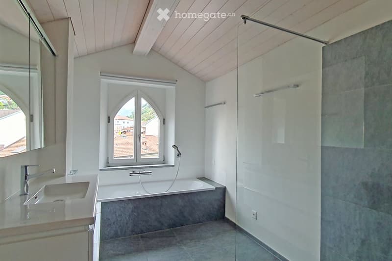 Modern bathroom with a large window, a bathtub, a sink, and a glass shower enclosure.