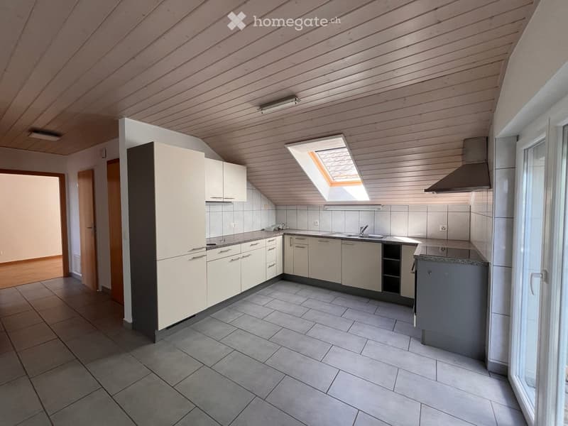 Modern kitchen with white cabinets, gray tiled floor, and a skylight window above the sink.