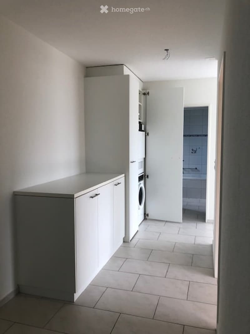 Modern kitchen with white cabinets, a countertop, and a washing machine in the corner.
