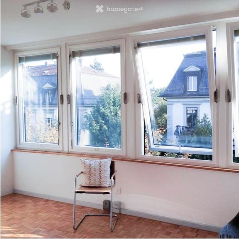 empty room with 3 windows, hardwood floor, chair, white walls