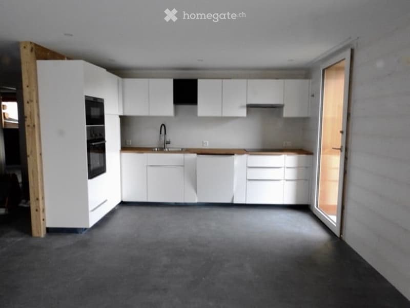 Modern kitchen with white cabinets, a sink, a faucet, and an oven. The space is clean and organized with a grey floor.