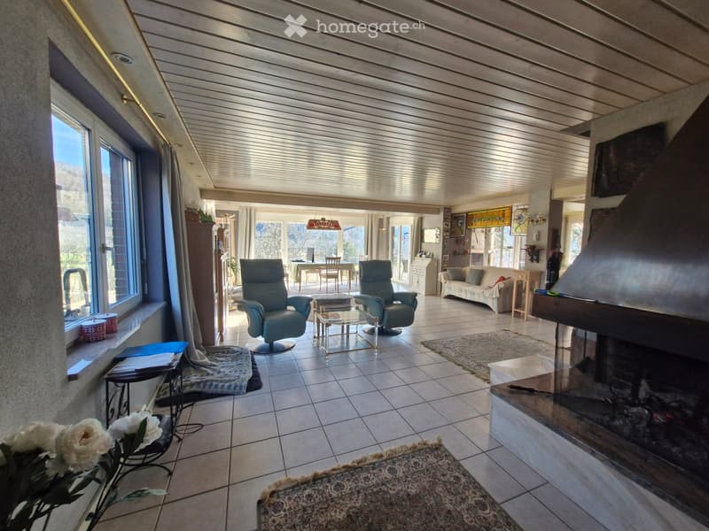 Fireplace, large windows, two armchairs, coffee table, rug, couch, side table, flowers