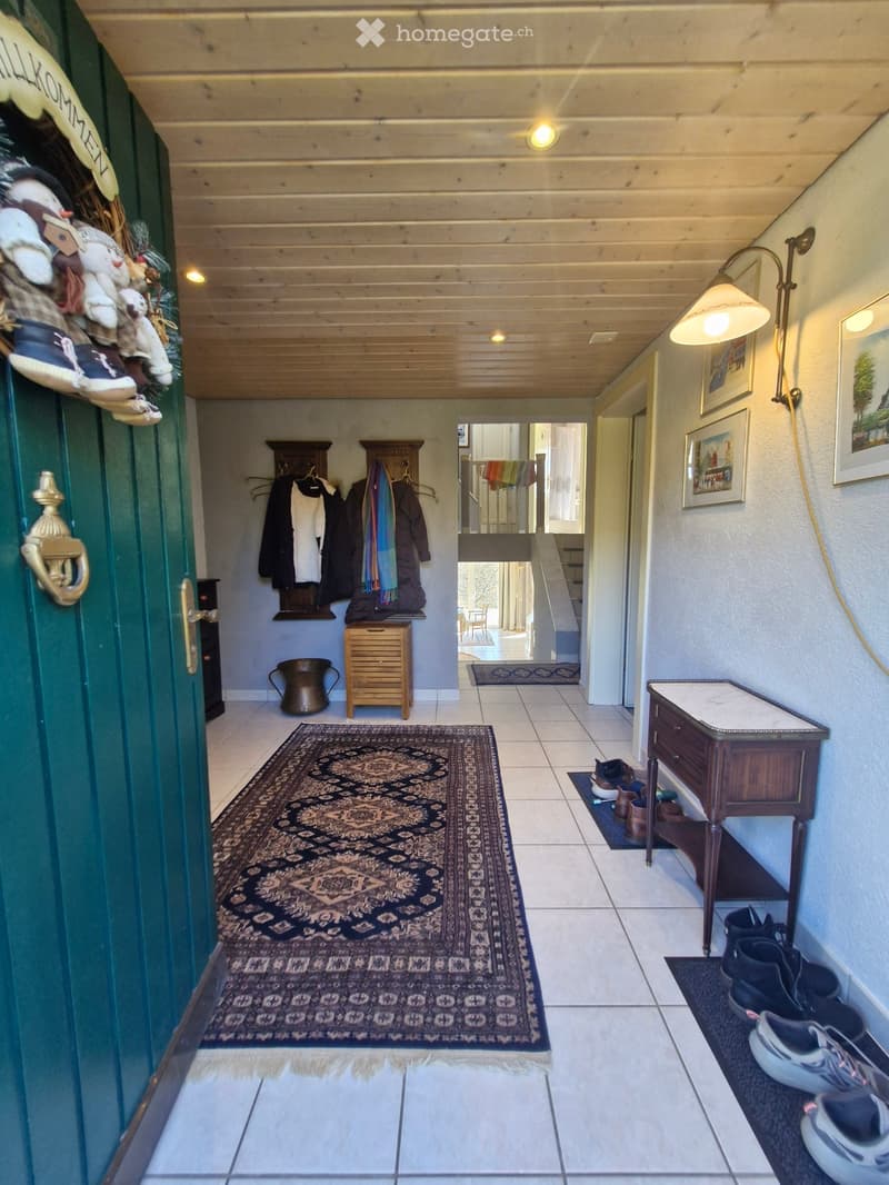 Entrance hall with rug, wooden cabinet, shoes, coat rack, lamps, framed pictures, wooden door
