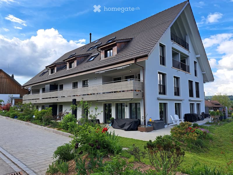 Modern two-story house with white exterior, multiple balconies, and a well-maintained garden.
