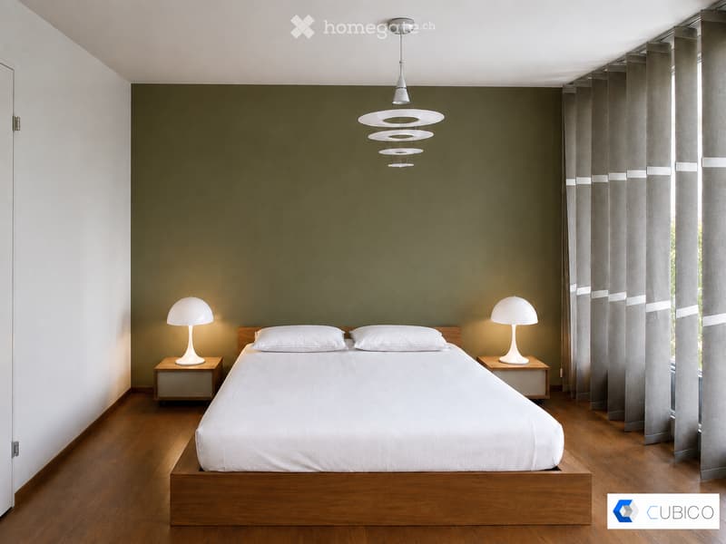 Modern bedroom with a wooden bed, white bedding, two nightstands with lamps, and large windows with grey curtains. The walls are painted in a two-tone design with dark green above and white below.