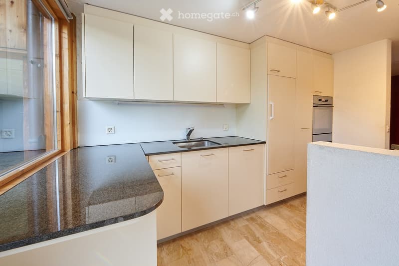 Modern kitchen with white cabinets, granite countertops, and a stainless steel sink. Features include a built-in oven and ample storage space.