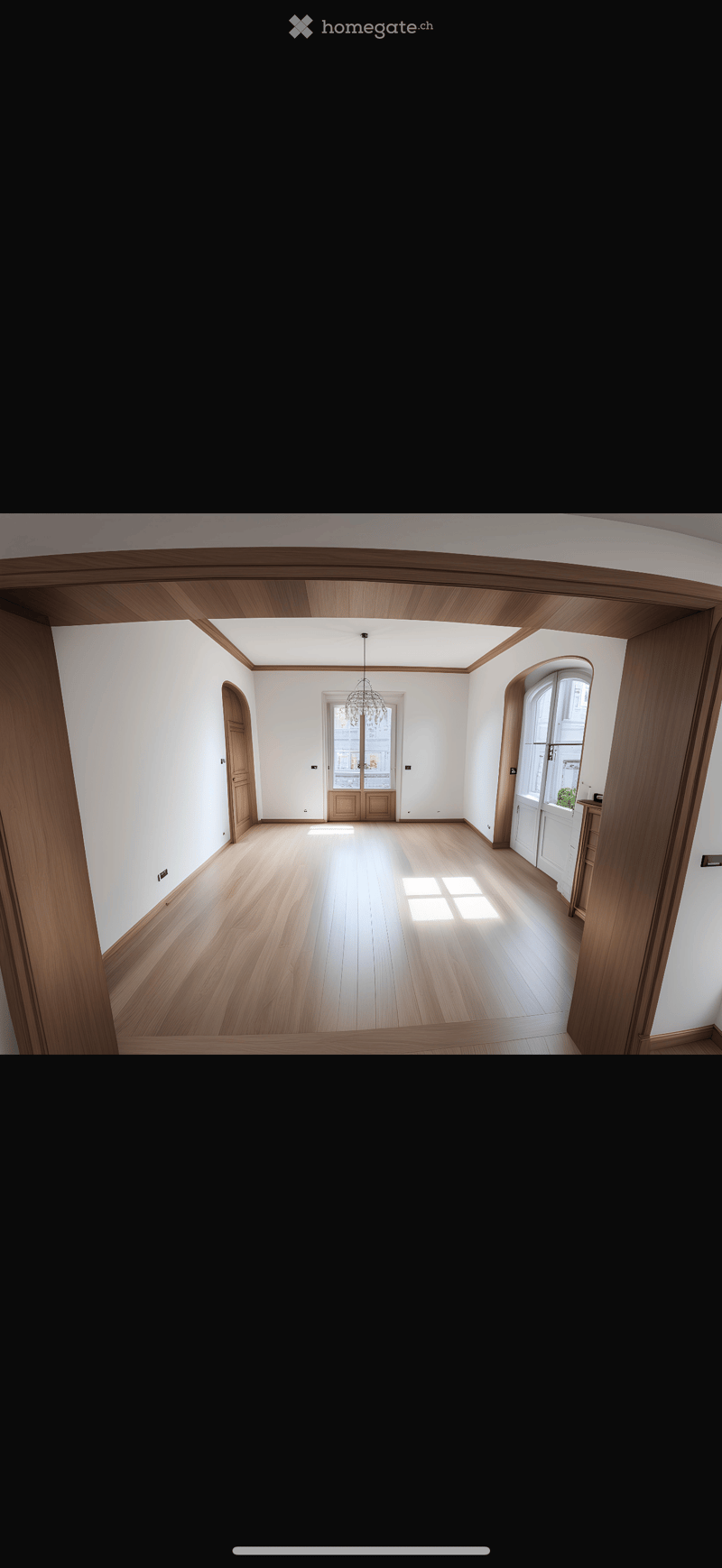 Empty room with wooden flooring, white walls, and large windows allowing natural light. The room features a chandelier hanging from the ceiling and several doors leading to other areas.