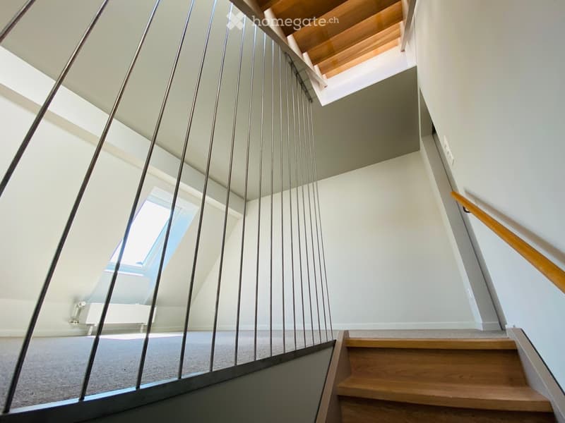 Modern staircase with wooden steps, metal railing, and skylight windows providing natural light.