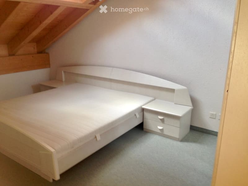 Bedroom with a single bed, white nightstand, and built-in shelving unit.