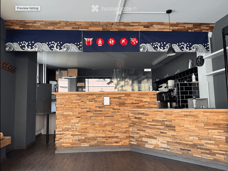 Modern reception area with a wooden counter, dark blue decorative banners, and shelves with various items.