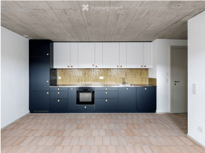 Modern kitchen with white upper cabinets, dark lower cabinets, and a tiled backsplash. Features an oven, sink, and a sleek, minimalist design.