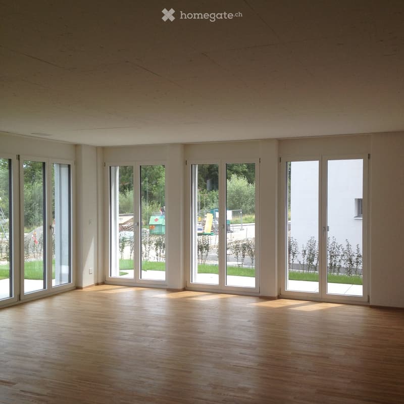 Empty room with wooden flooring and large glass doors leading to an outdoor area.