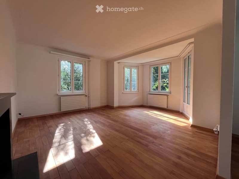 Empty room with wooden flooring, large windows, radiators, and natural light. No furniture or equipment present.