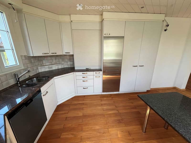 Modern kitchen with white cabinets, stainless steel appliances, granite countertop, and wooden flooring.